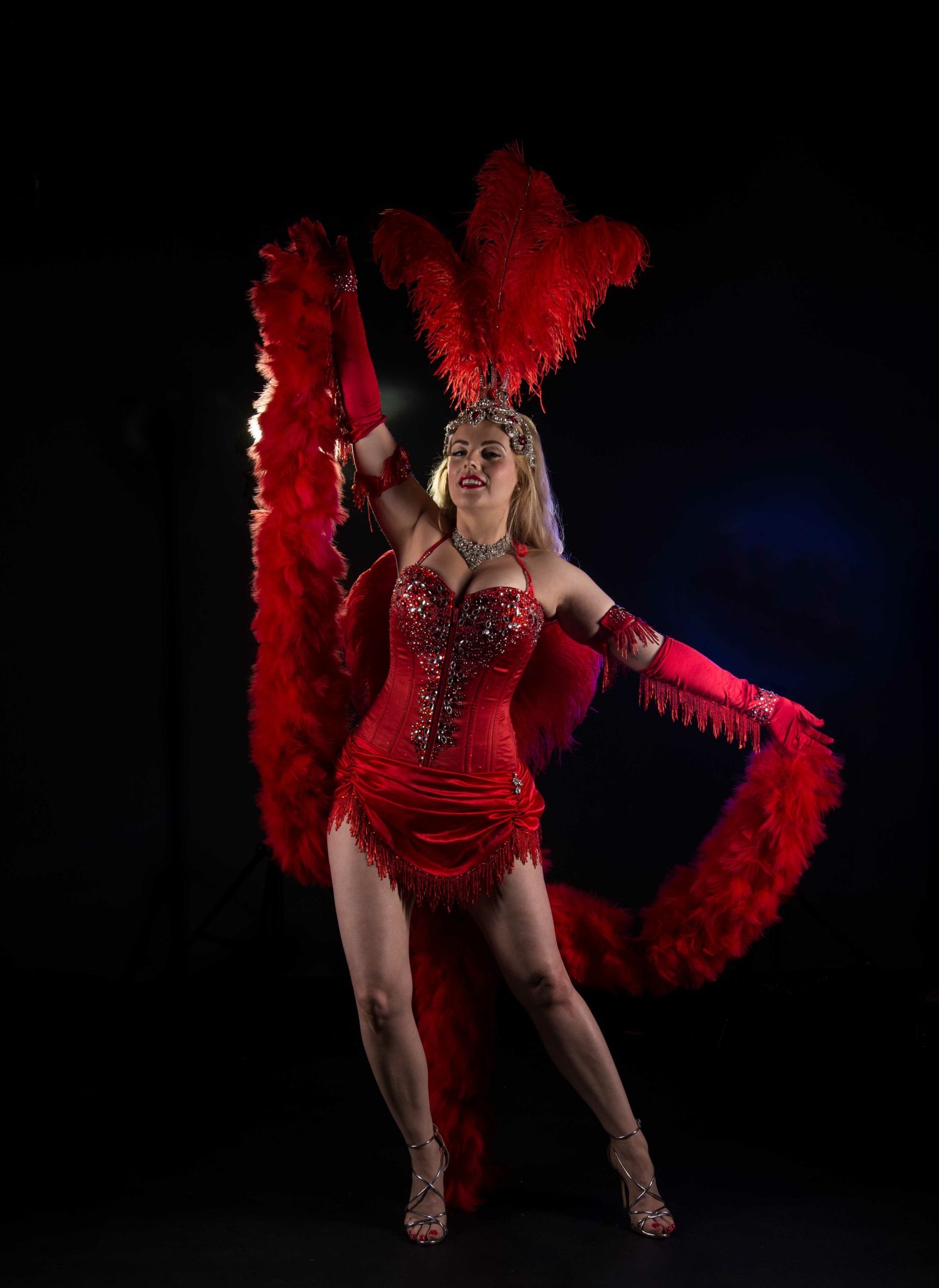 Showgirl Burlesque act red outfit red feathered headdress and tail on black background