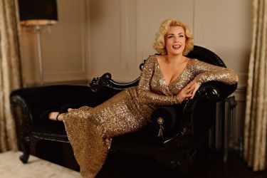 fashion model classic marilyn monroe chaise lounge pose wearing gold long dress 