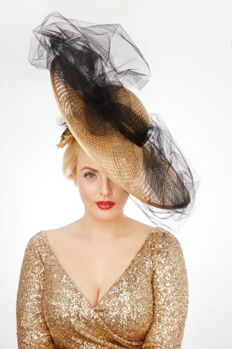 fashion model in gold dress with matching gold hat with black veil decoration 