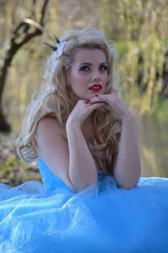 fashion model in pale blue dress next to riverside setting