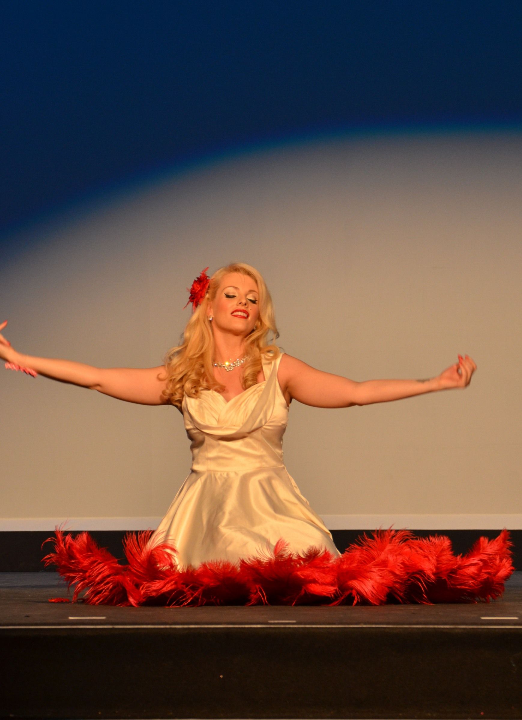 feathered kisses act kneeling on stage behind long feathered prop