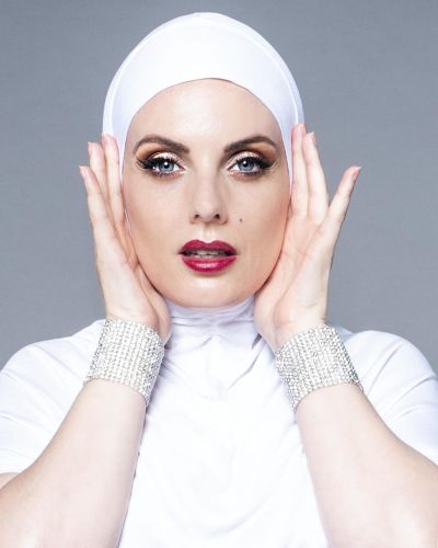 fashion model in white with white head scarf and glistening wrist bands